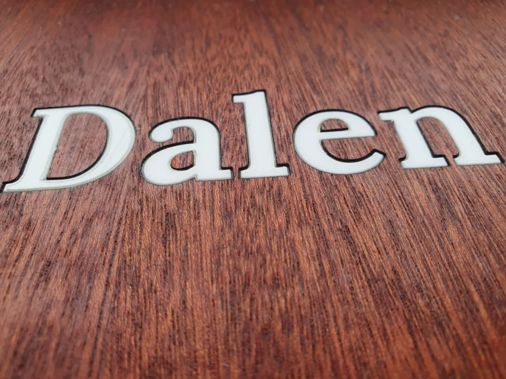 Close-up van ingelegde witte plexiglas naamletters – ambachtelijke inlay-techniek – Model 6 Wooddes